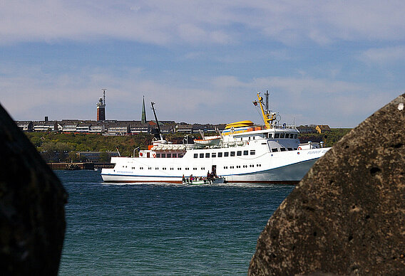 Ein Börteboot liegt vor dem Schiff Funny Girl. Im Hintergrund ist die Insel Helgoland zu sehen.