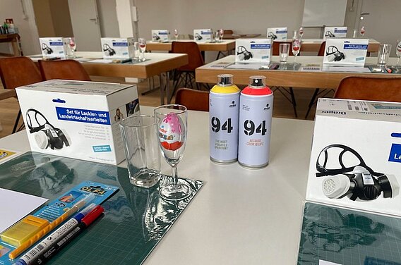 Spraypainting Workshop Ausstattung auf einem Tisch. Sprühdosen, Sprühmaske, Schneidematte und Cutter 
