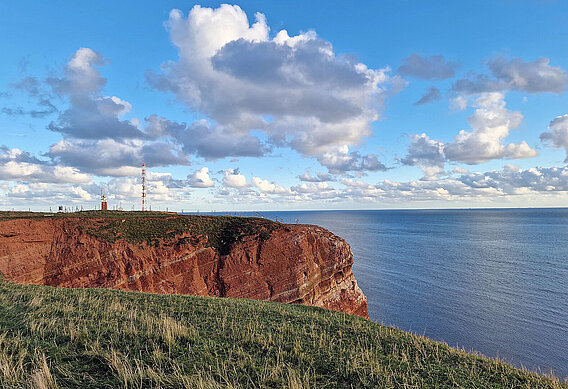 Das Bild zeigt das Oberland von Helgoland. Am Felsrand stehend, sieht man das blaue Meer.