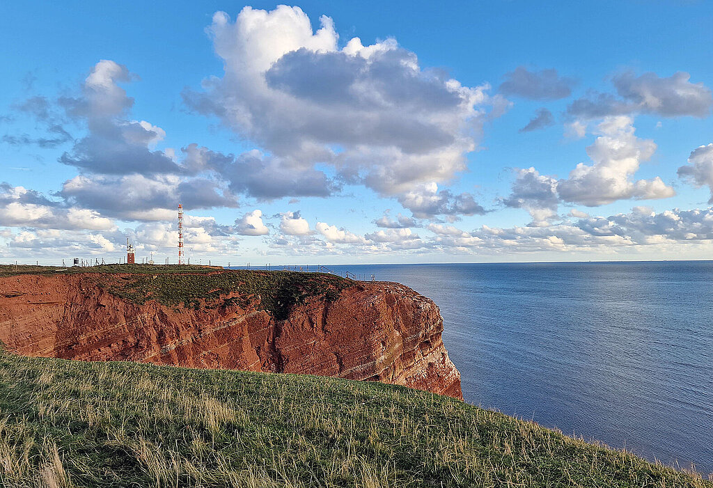 Das Bild zeigt das Oberland von Helgoland. Am Felsrand stehend, sieht man das blaue Meer.